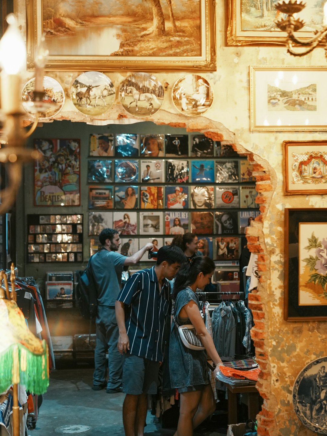 Three people browse clothing racks inside a vintage store.