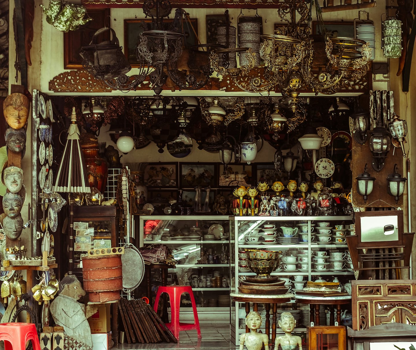 Antique shop storefront filled with chandeliers, lamps, and decor.